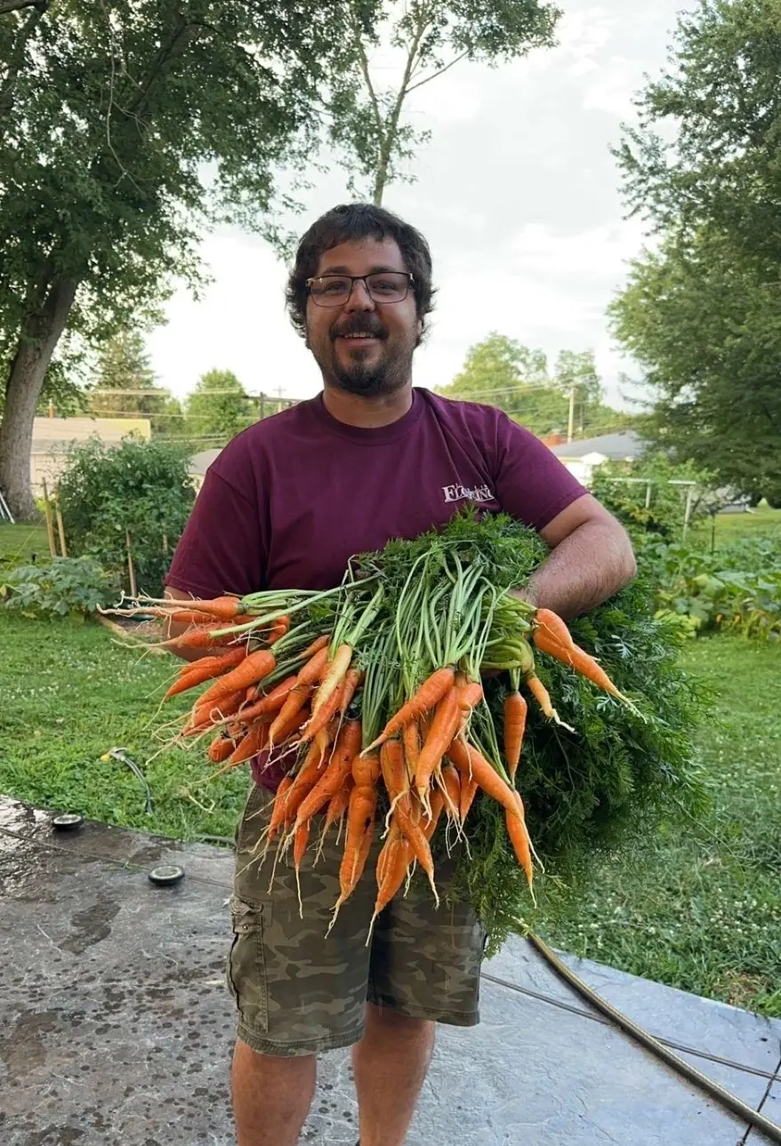 Tyler Mullen holding a large harvest of fresh organic carrots from The Sanctuberry backyard garden in Latrobe, PA